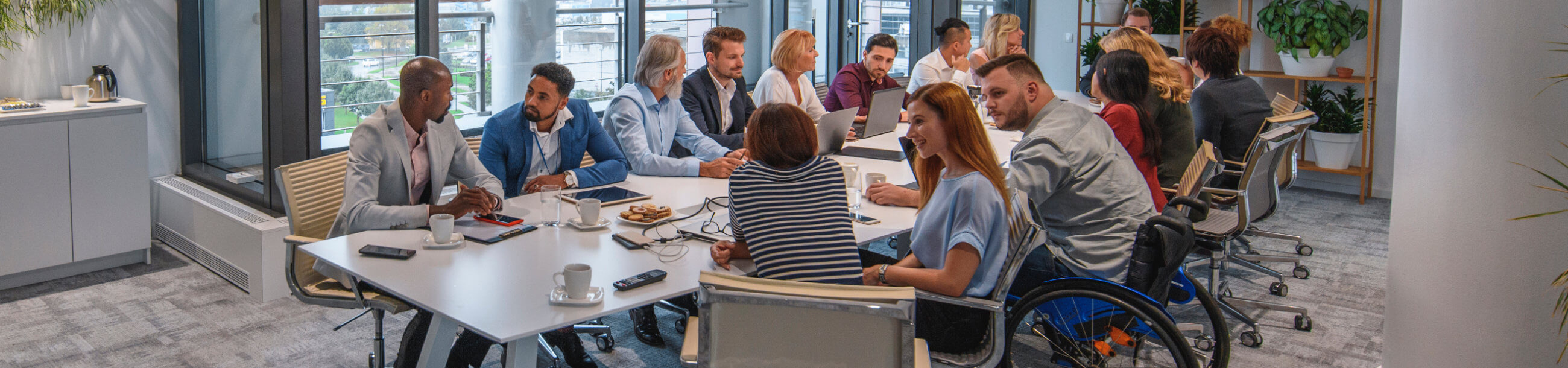 a group of professionals in an office discussing along a white table