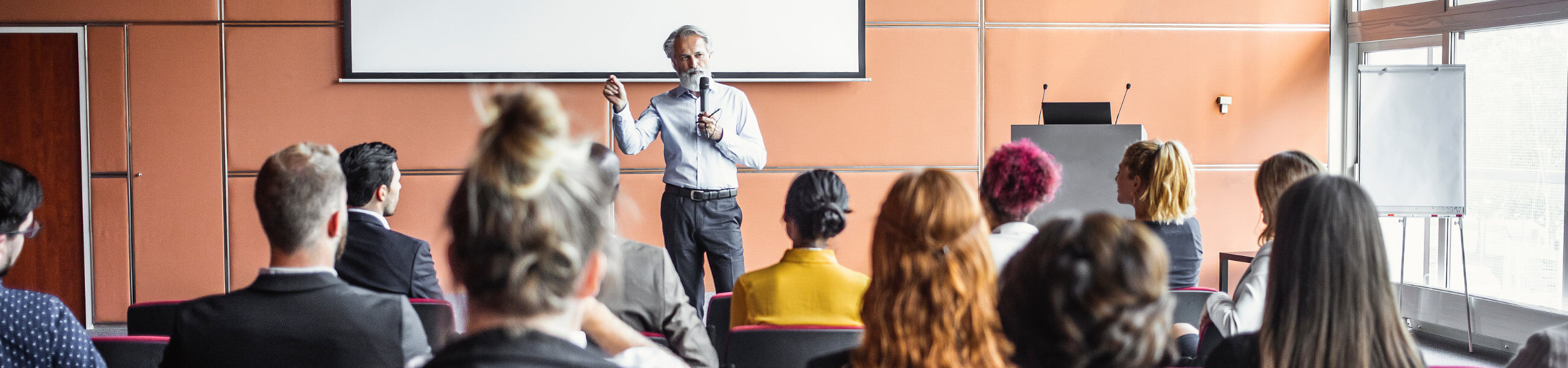 man with a microphone speaking in front of a group of people